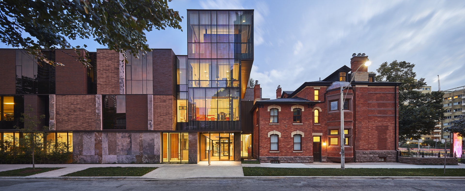 Exterior of Casey House showing front glass facade lit from within