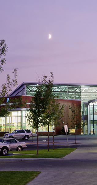 Walkway to Illuminated Front Facade of Brick and Glazing Under a Magenta Moon-lit Sky