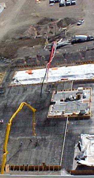 Aerial View of Two Concrete Pumping Truck Arms Articulated Over Rebar Laced Pad