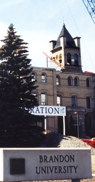 Cupola Tower Temporarily Supported by Steel Beams Atop Masonry Building Facade with University Sign in Forground