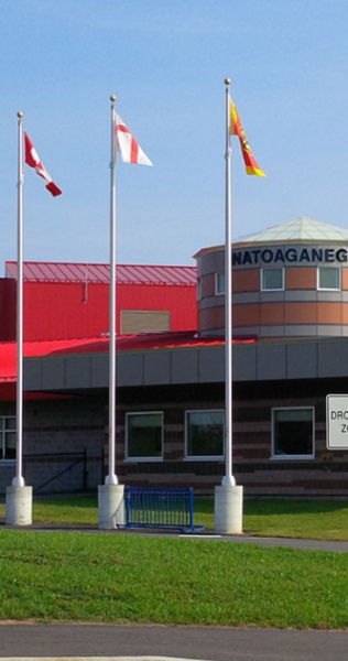 Exterior of the Natoaganeg School showing three flagpoles 