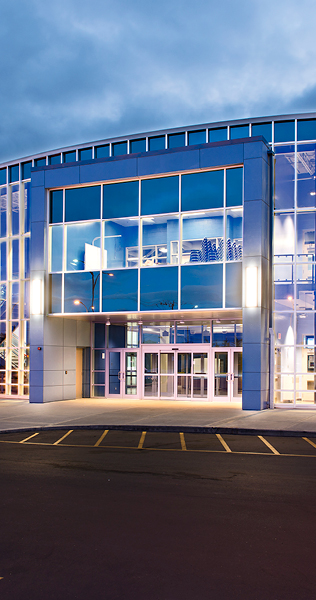 Illuminated Glazed Facade with Front Entrance Against a Night Sky