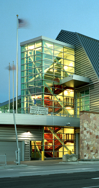 Illuminated Glazed Stairwell Tower Against a  Stone and Paneled Facade