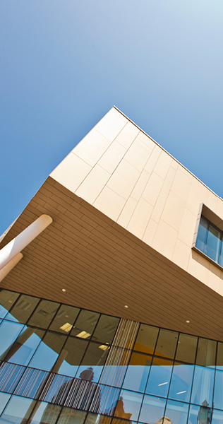 Upward view of unique overhang of building showing wood cladding and windows