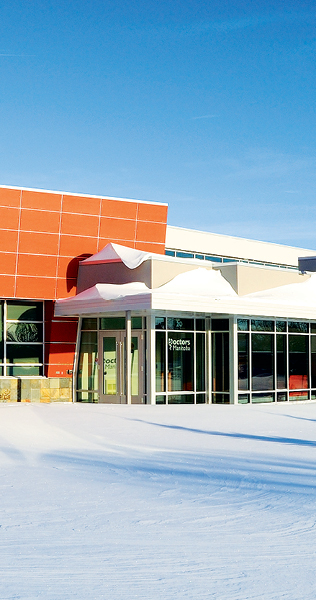 Exterior of the Manitoba Medical Association showing the front entrance and orange cladding on a snowy day