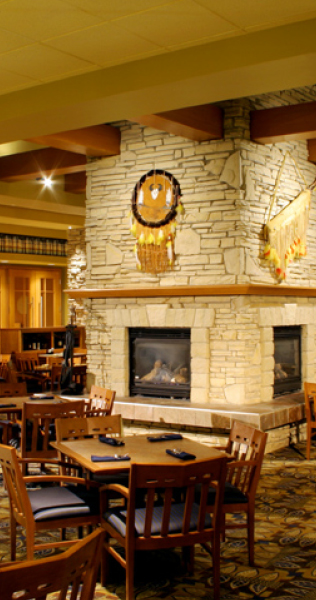 Interior of the Sawridge Hotel restaurant showing a stone-clad fireplace in the centre of the room