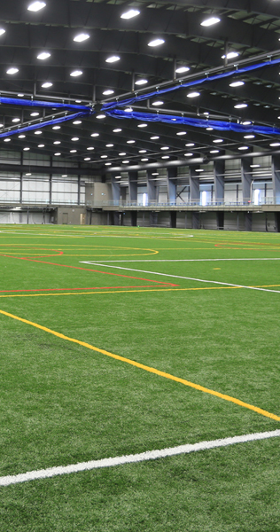 Interior of the Winnipeg Indoor Soccer Complex showing green grass fields and ceiling lights