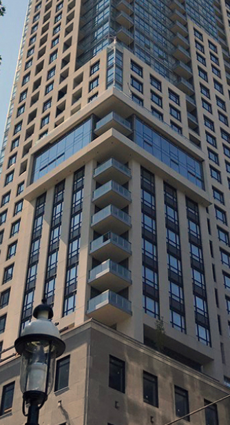 Building Facade Featuring the Envelope Elements of Stone and Punch Windows in Pedestal Progressing to Concrete and Glazing