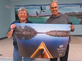 Bird employee posing with a piece of art work and a member of a First Nations community at an event