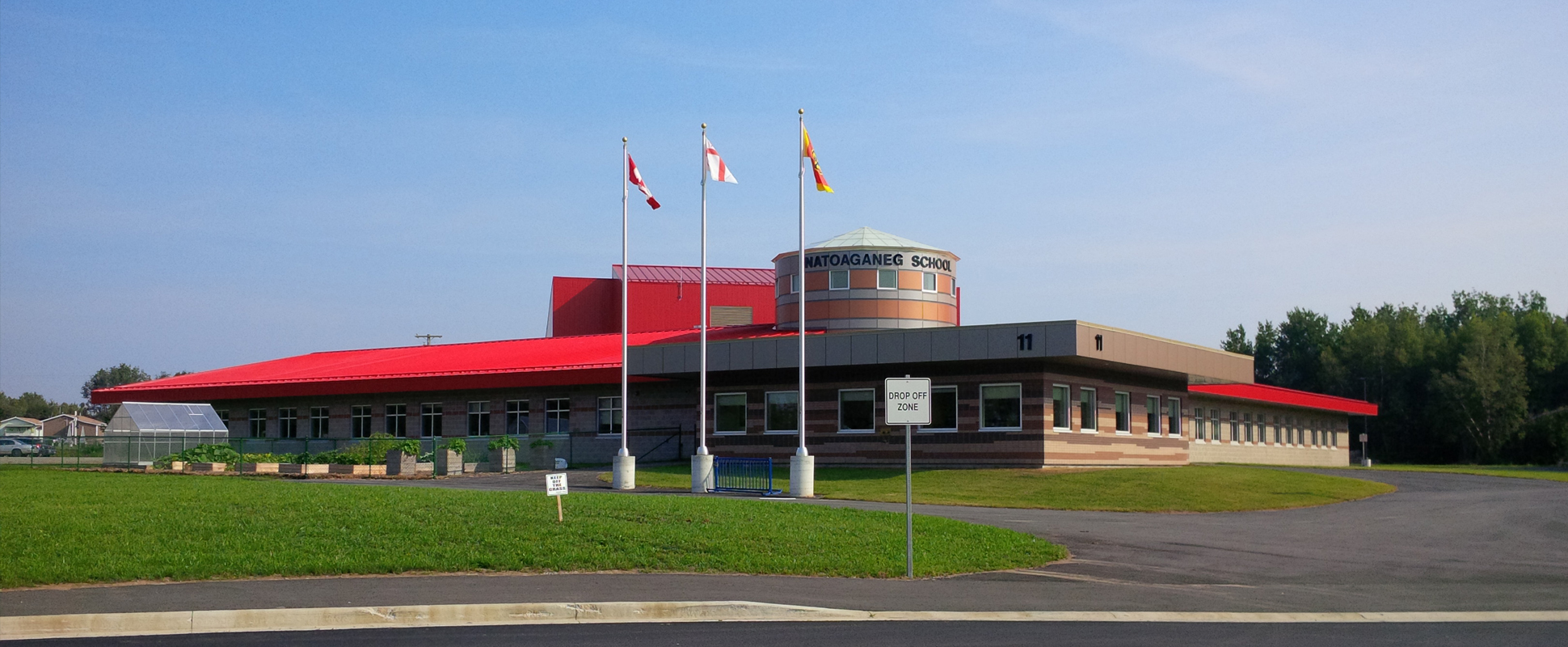 Natoaganeg School exterior with three flagpoles in foreground
