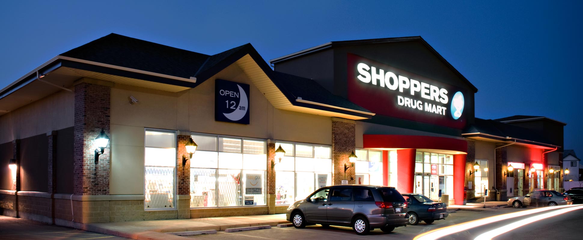 Saddletowne Shops exterior lit at night, showing retail store signage 