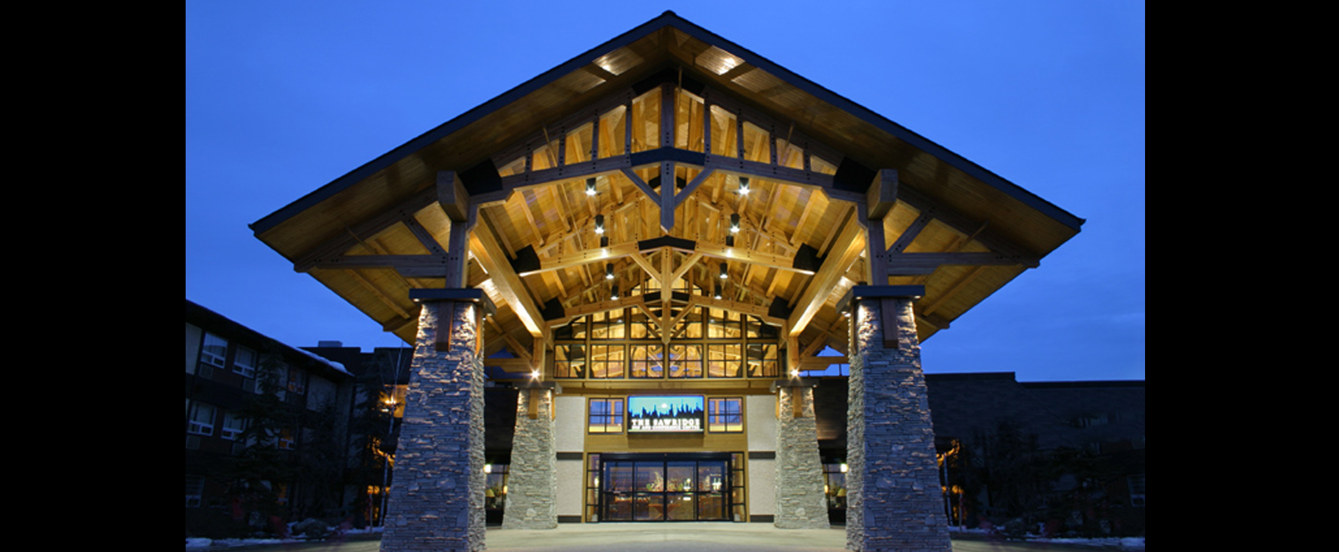 Sawridge Inn and Conference Centre entrance lit up at night to highlight portico roof